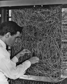 black and white photo of man adjusting a mess of wiring