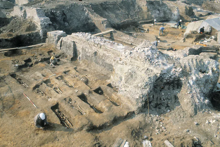 An excavation, showing skeletons in graves.