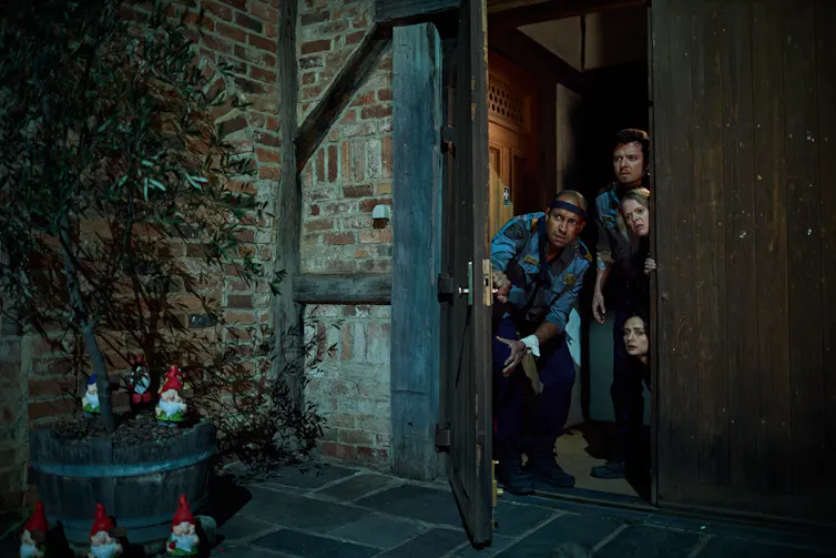 Cops peer out a doorway; garden gnomes surround a potted tree.