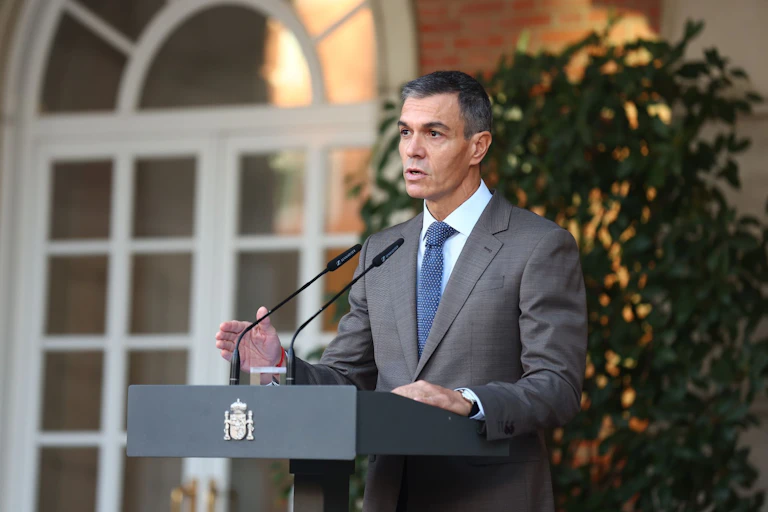 Pedro Sánchez speaking into a microphone on a lectern.