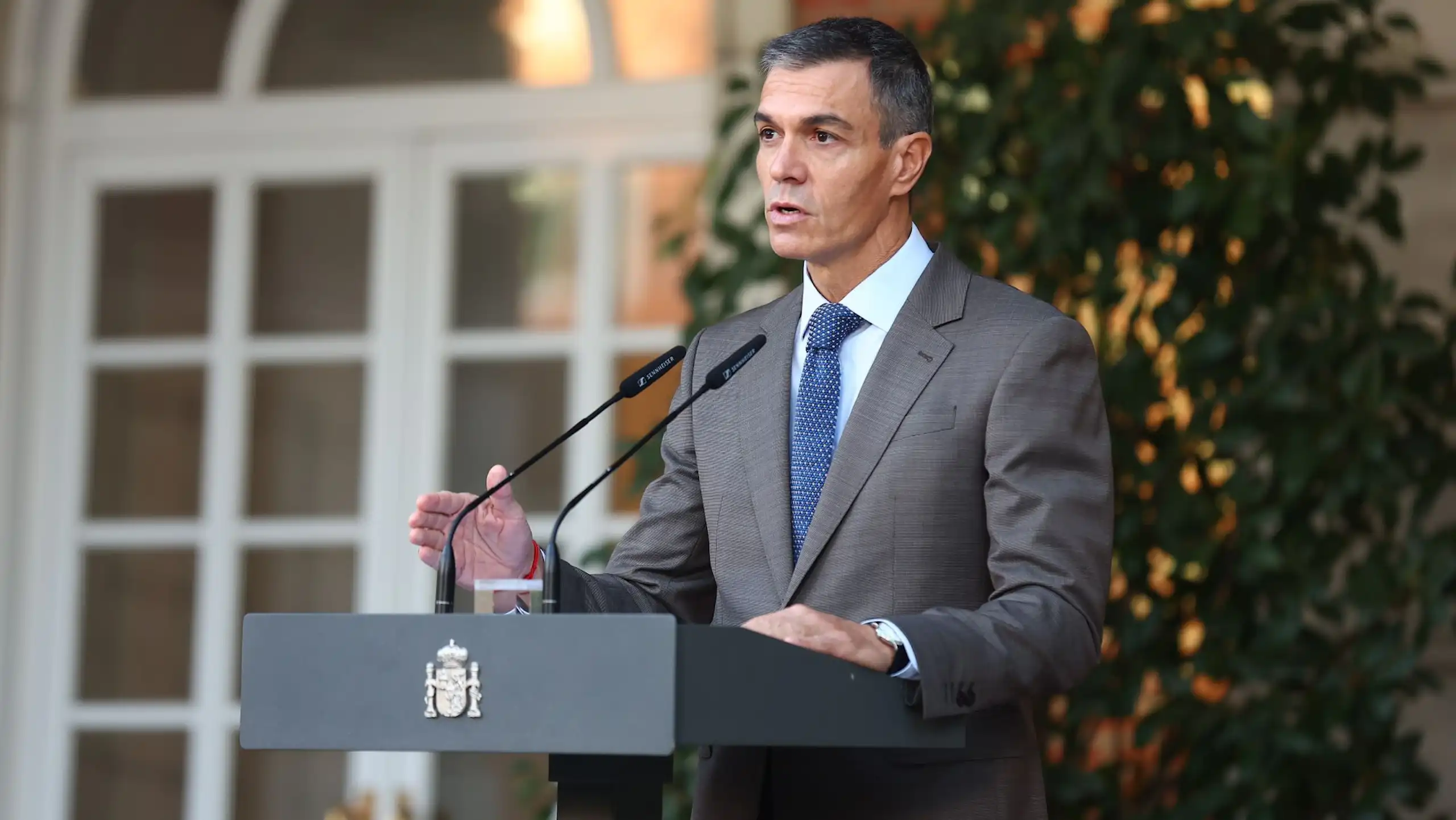 Pedro Sánchez speaking into a microphone on a lectern.