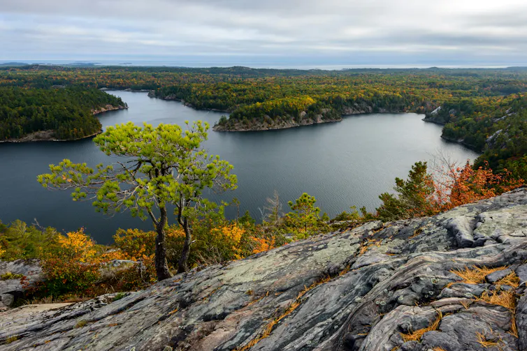 A photo of a remote Ontario lake in the wilderness with Canadian shield rock in the foreground.