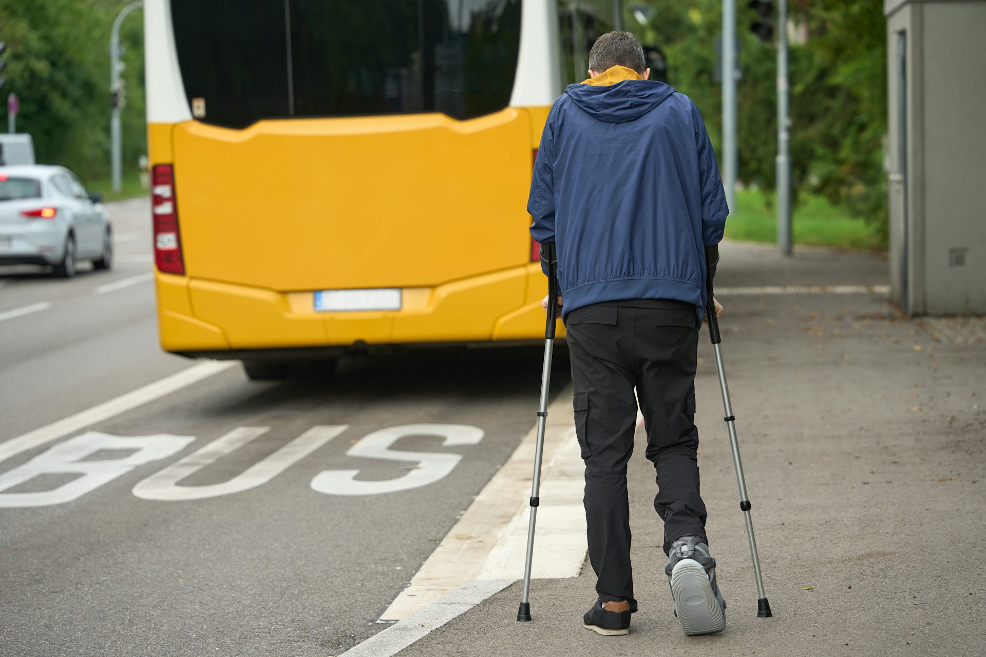 Person walking with crutches tries to hurry to catch a bus