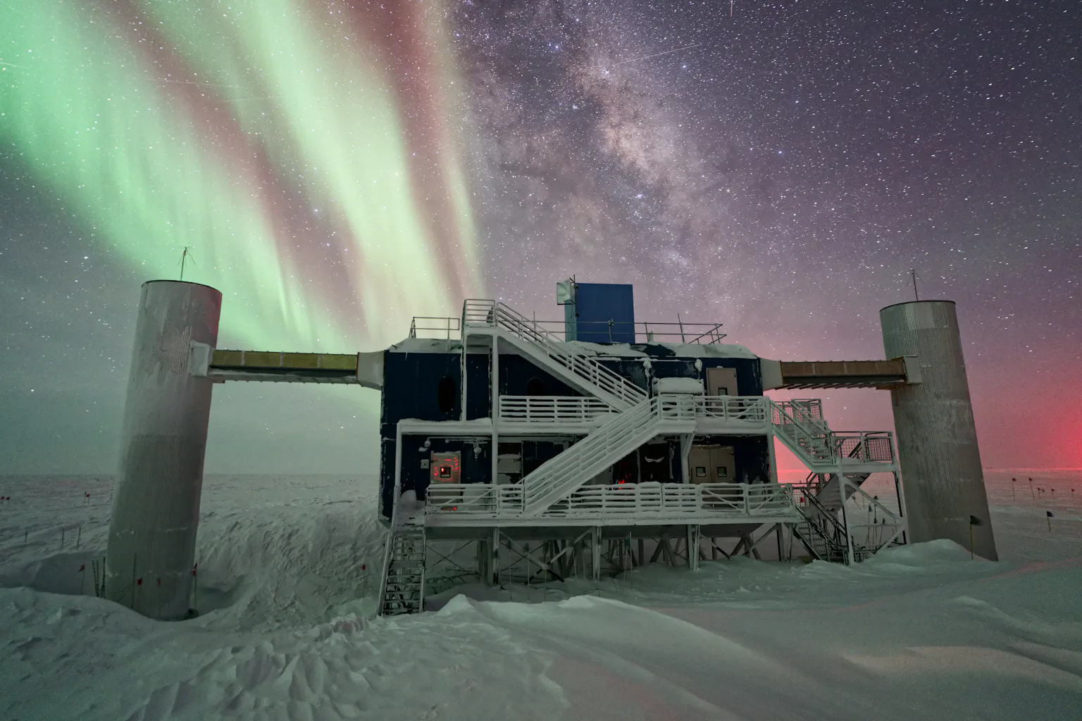 building on snowy ground with aurorae in the night sky