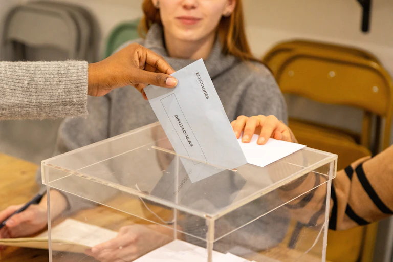 Mano depositando el voto en una urna