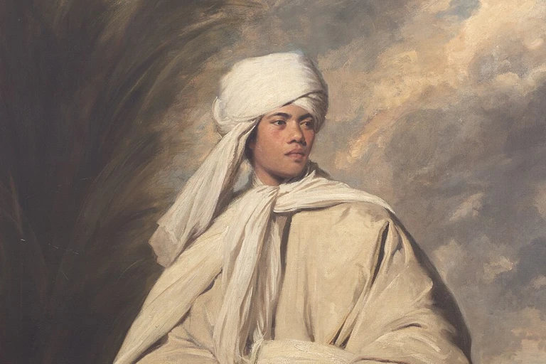 Young man wearing a turban and flowing cloak striking a fierce pose.