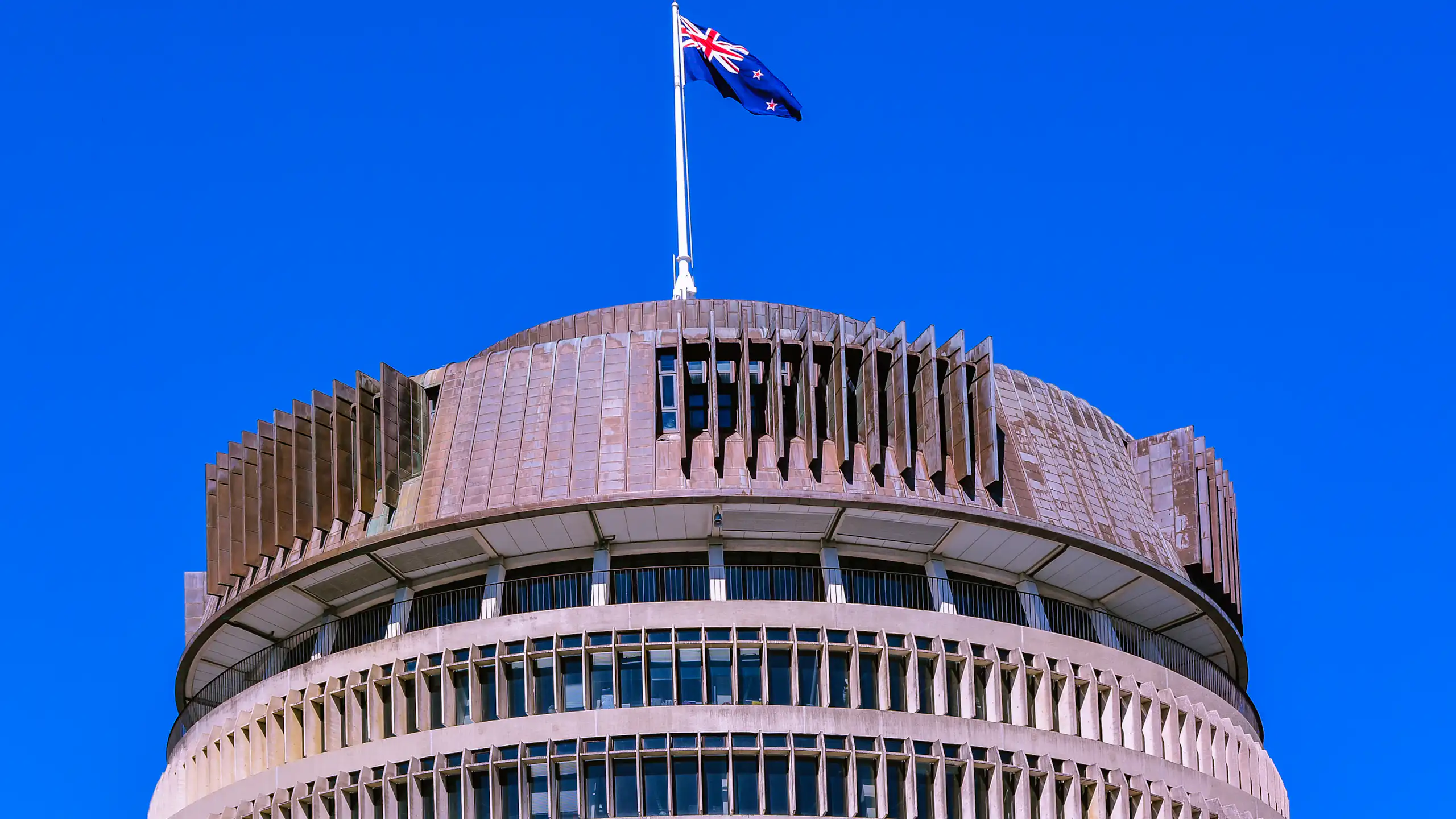 Beehive building in Wellington with flag flying against blue sky