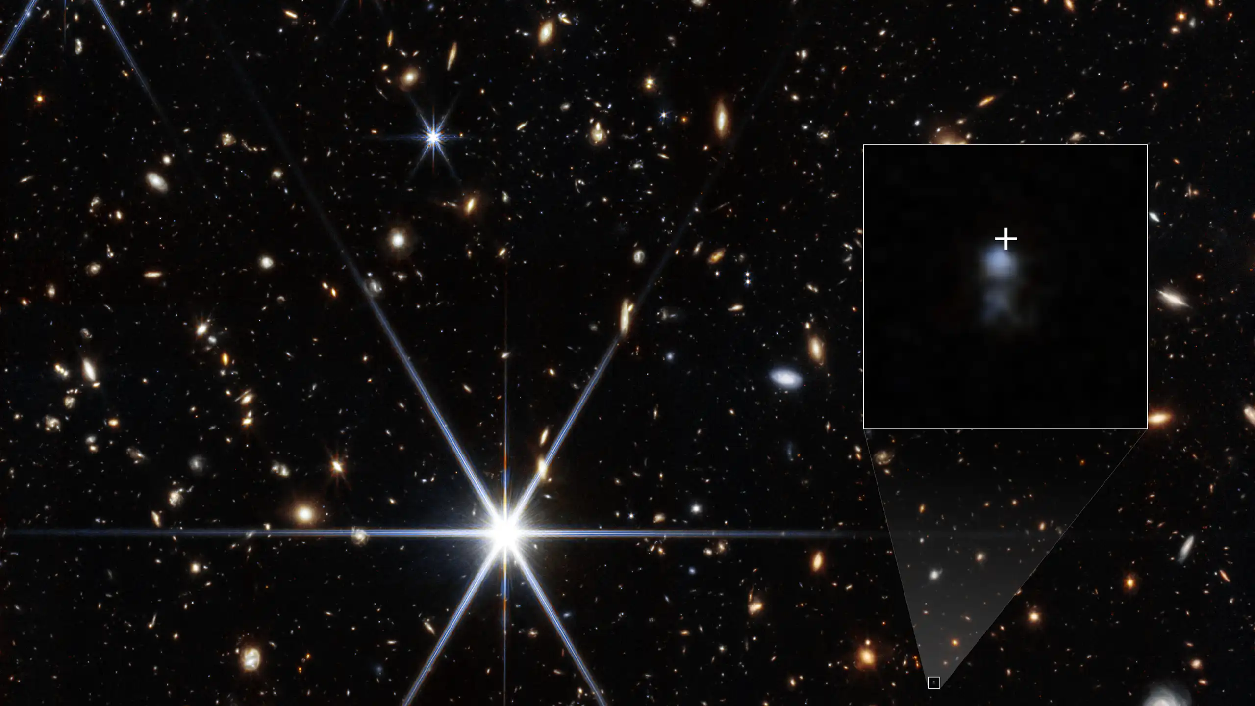 Photograph of the location of the fast radio burst taken by the James Webb Space Telescope’s Near-Infrared Camera. The host galaxy is shown by an inset along with a white cross marking the location where the radio signal originated from.