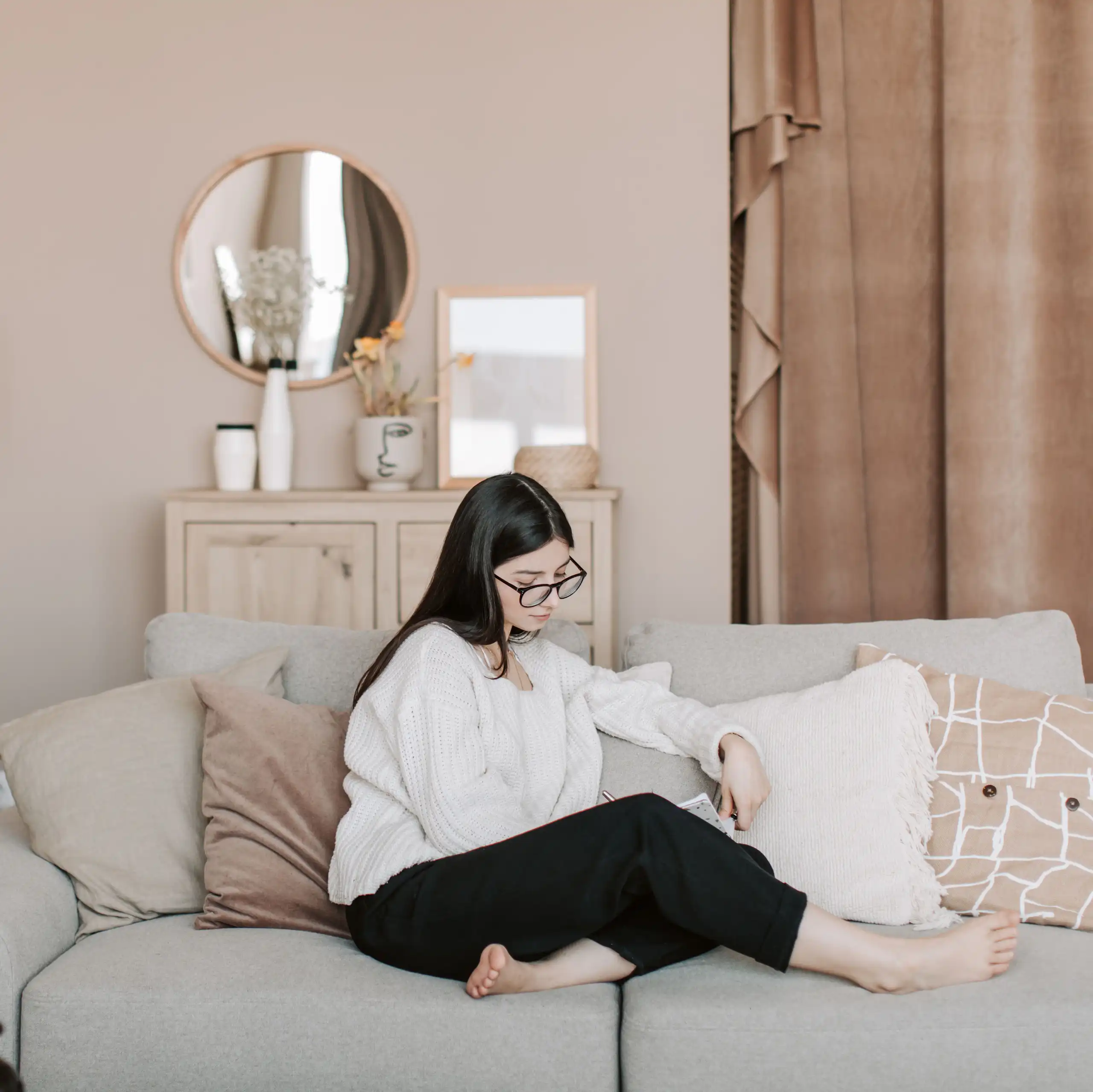 A young woman sits casually on a couch in a very blandly-coloured lounge.