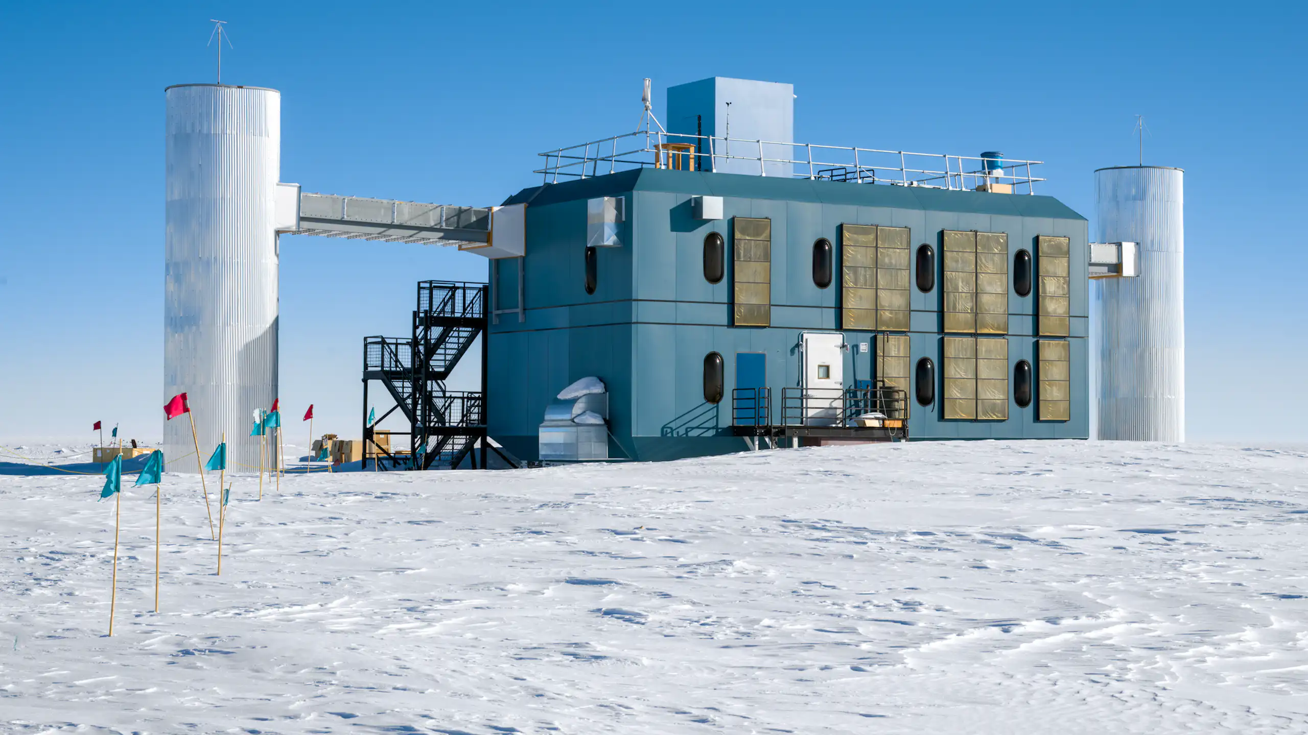 The IceCube research station, a rectangular building with three pillars attached, sitting on snowy ground.