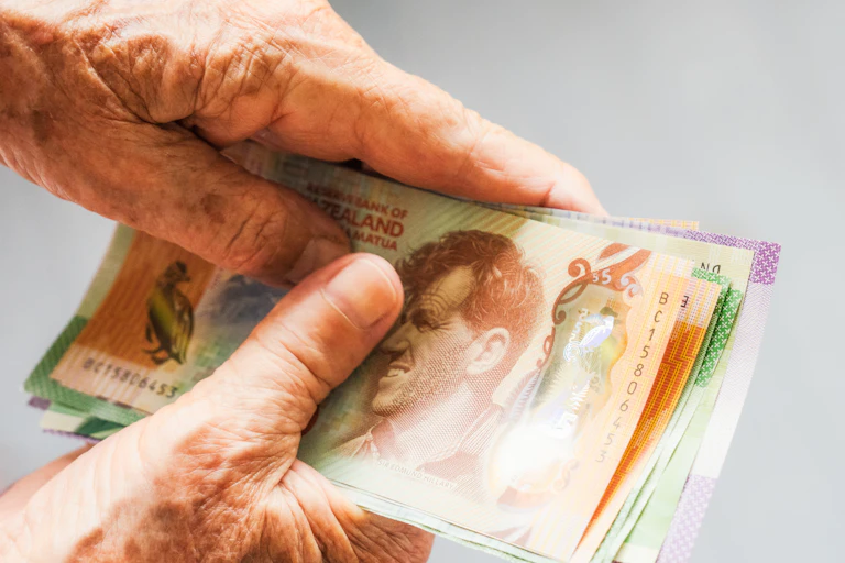 Older person's hands holding New Zealand banknotes