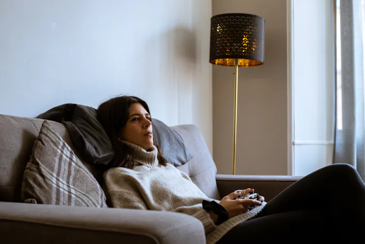 A woman sitting on the sofa wearing a polo neck.