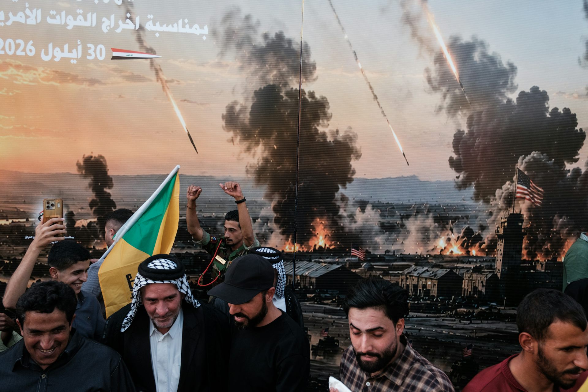 People poses for photos in front of a picture showing a war scene.