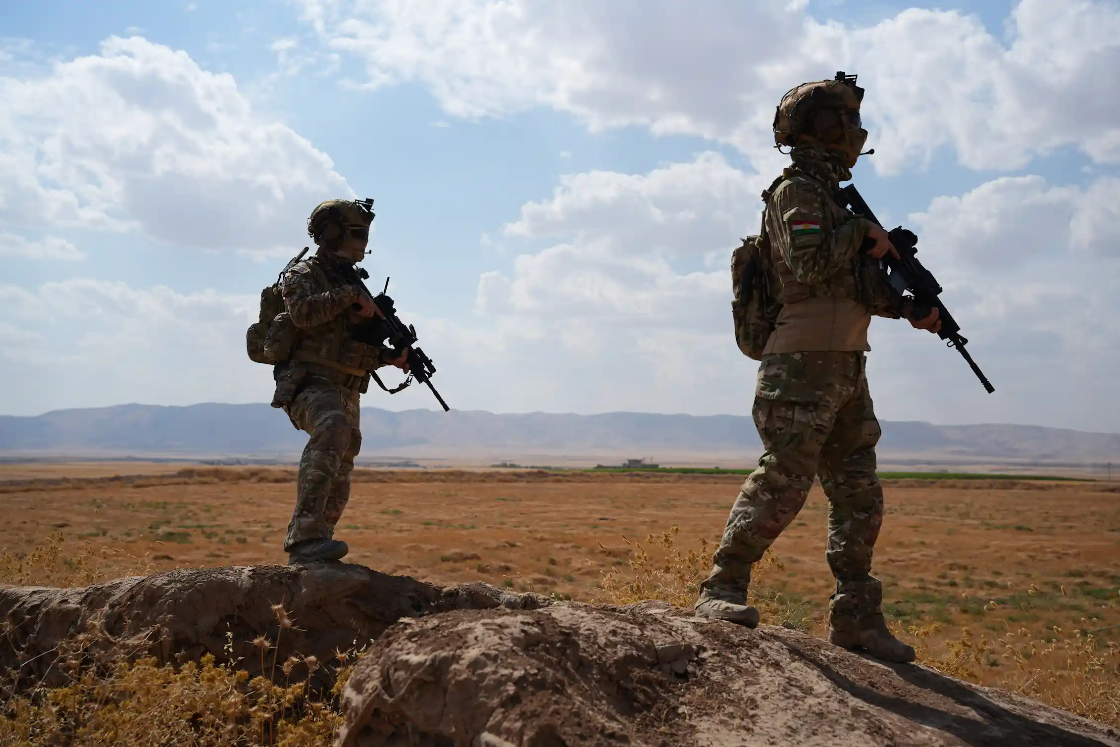 Two soldiers on patrol in the countryside.