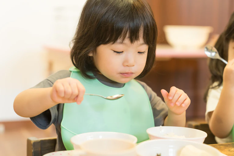 Una nena amb aspecte oriental menja de tres plats.