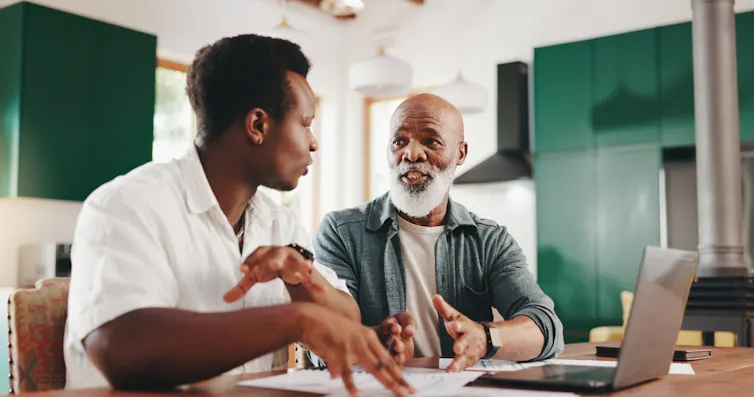 A younger man in discussion with an older man, possibly his father or grandfather.