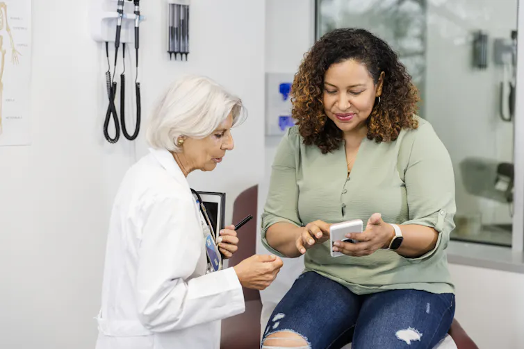 woman looking at phone with her doctor