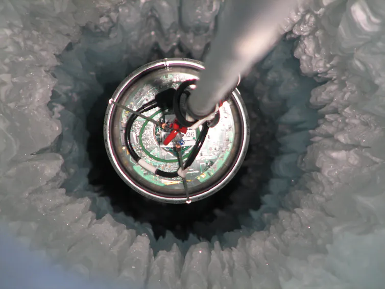 A metal rod stuck into a deep hole in the ice