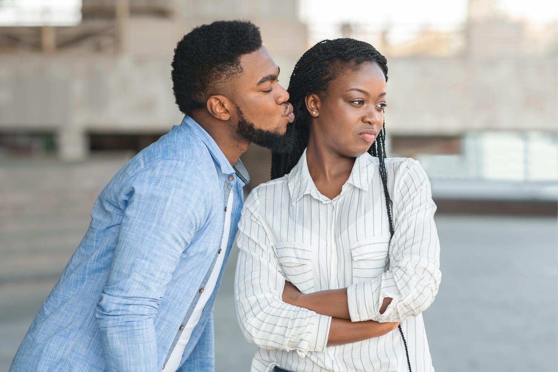 Um homem se inclinando para beijar uma mulher na bochecha, enquanto ela se vira