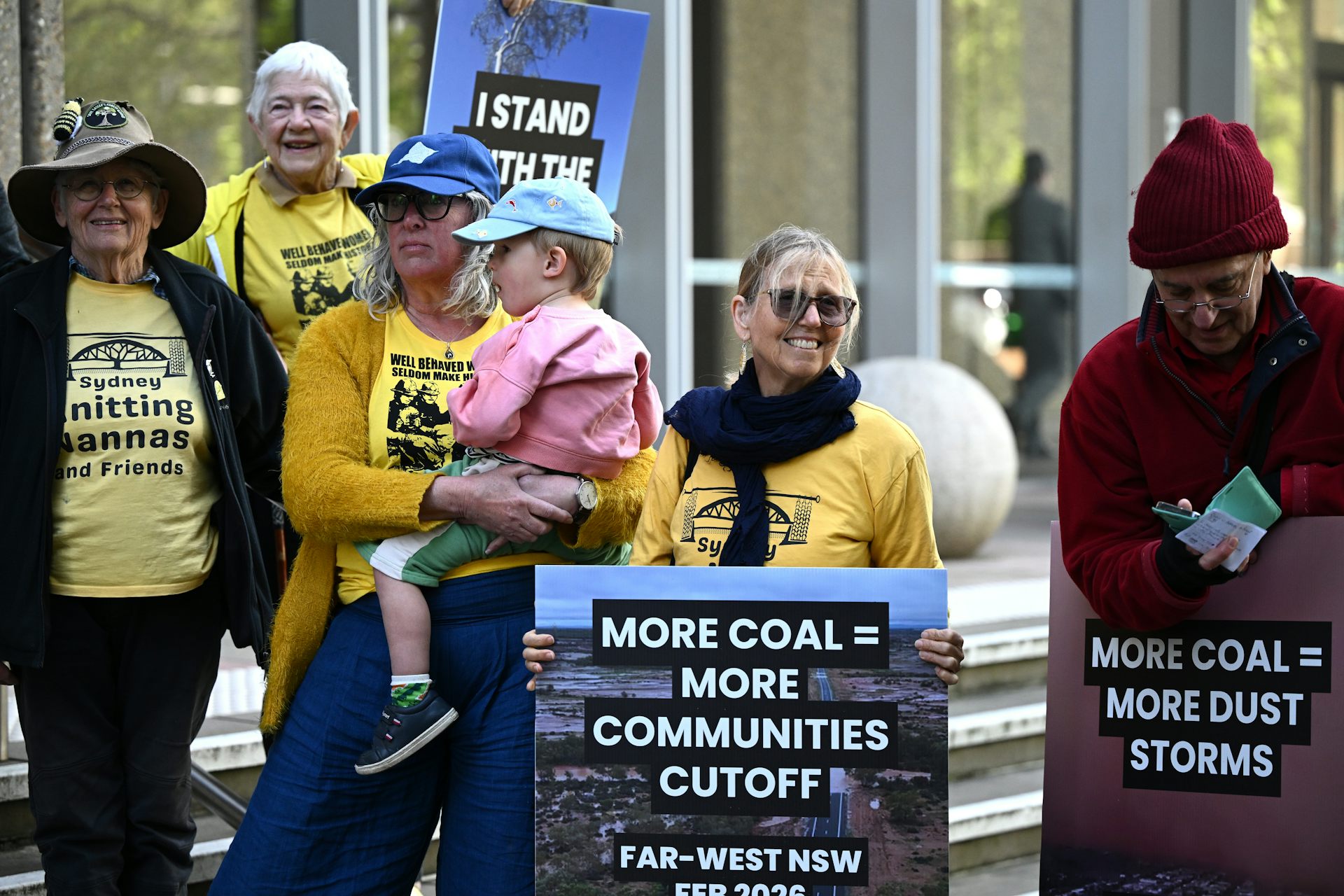 Community members gather outside the High Court of Australia, holding placards about coal mine.