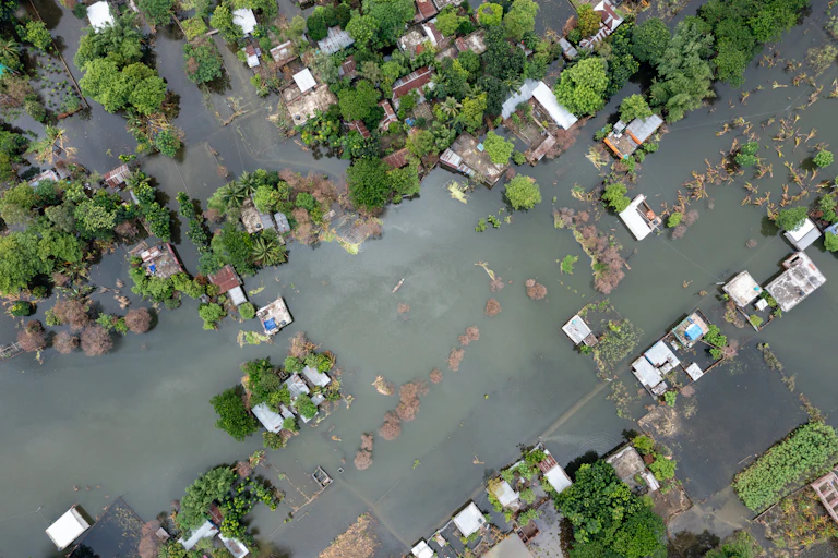 aerial view of flooded village, water filling streets. tropical trees.