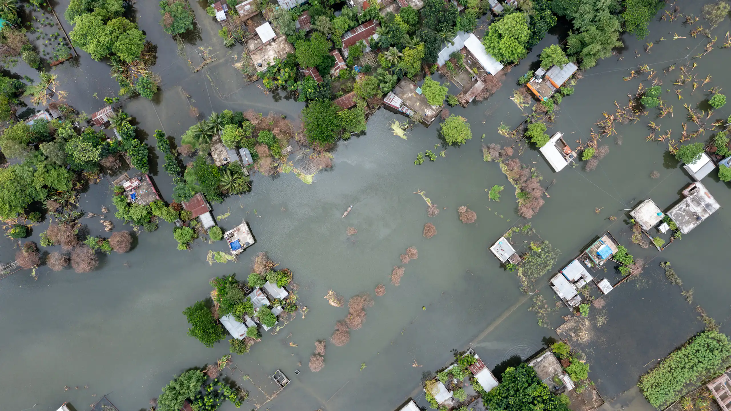 aerial view of flooded village, water filling streets. tropical trees.