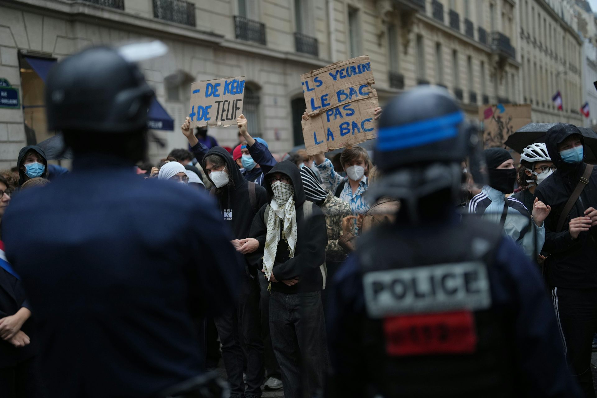 Protesters hold up signs as they are confronted by police.
