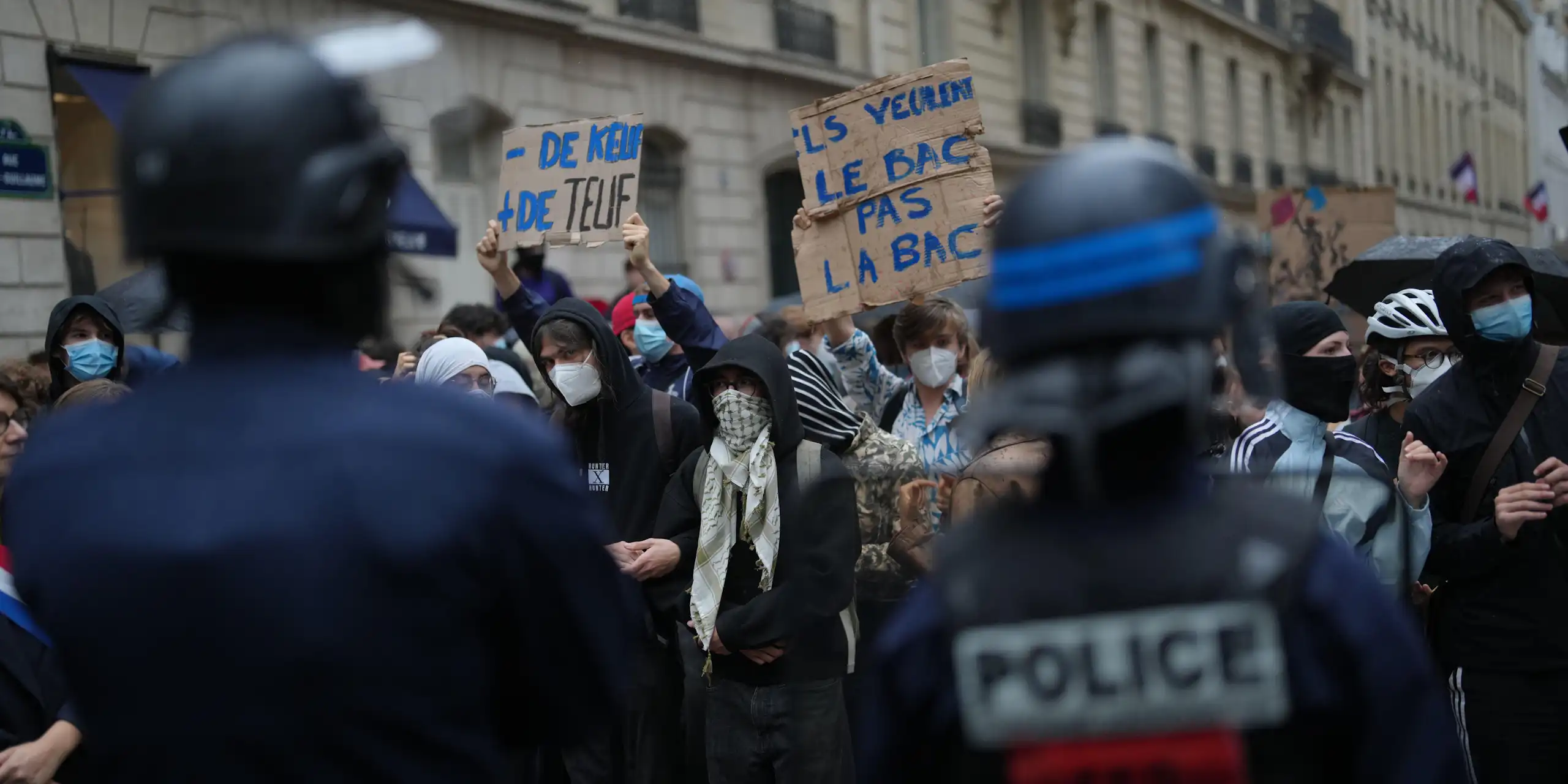 Protesters hold up signs as they are confronted by police.