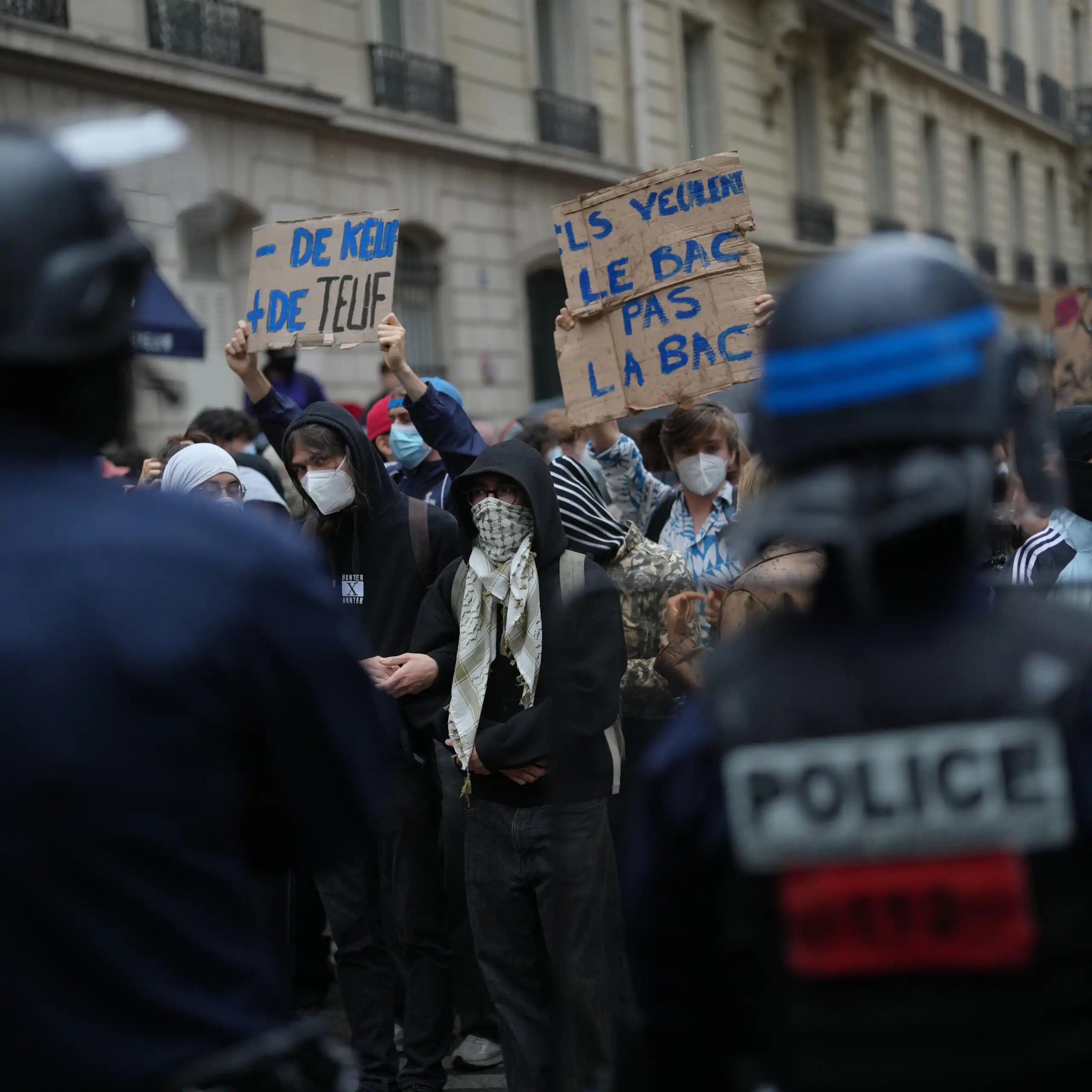 Protesters hold up signs as they are confronted by police.