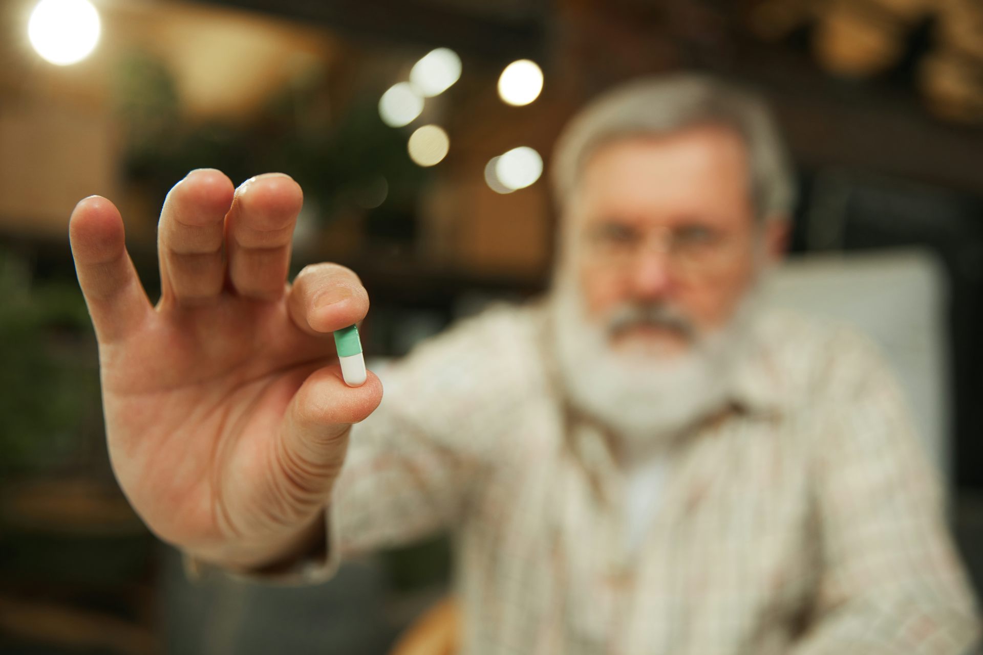 Man holding supplement pill to camera