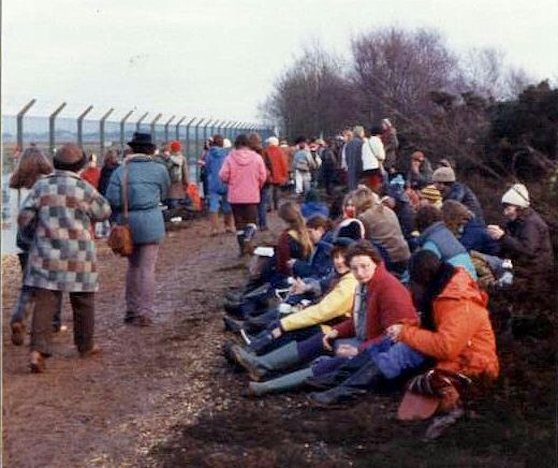 Crowds of women sitting and walking outside the Greenham Common military base