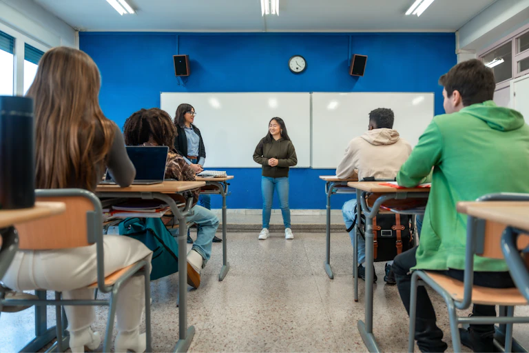 Una chica se dirige a sus compañeros en un aula