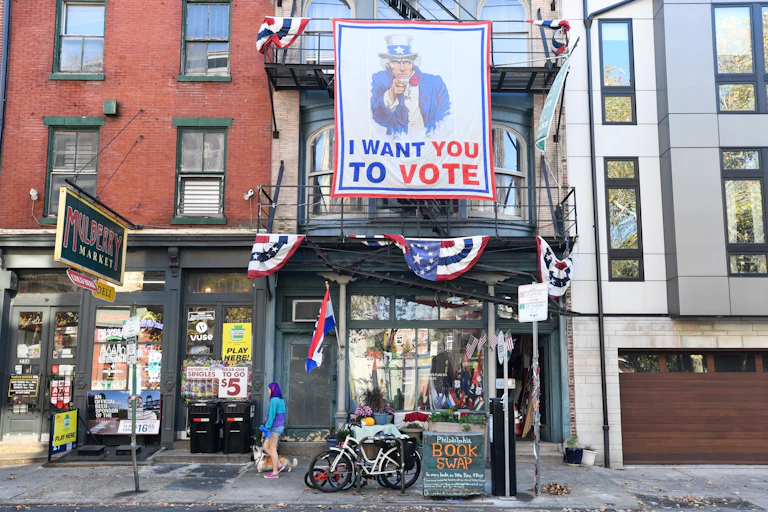 A sign encouraging people to vote hangs from the facade of a building
