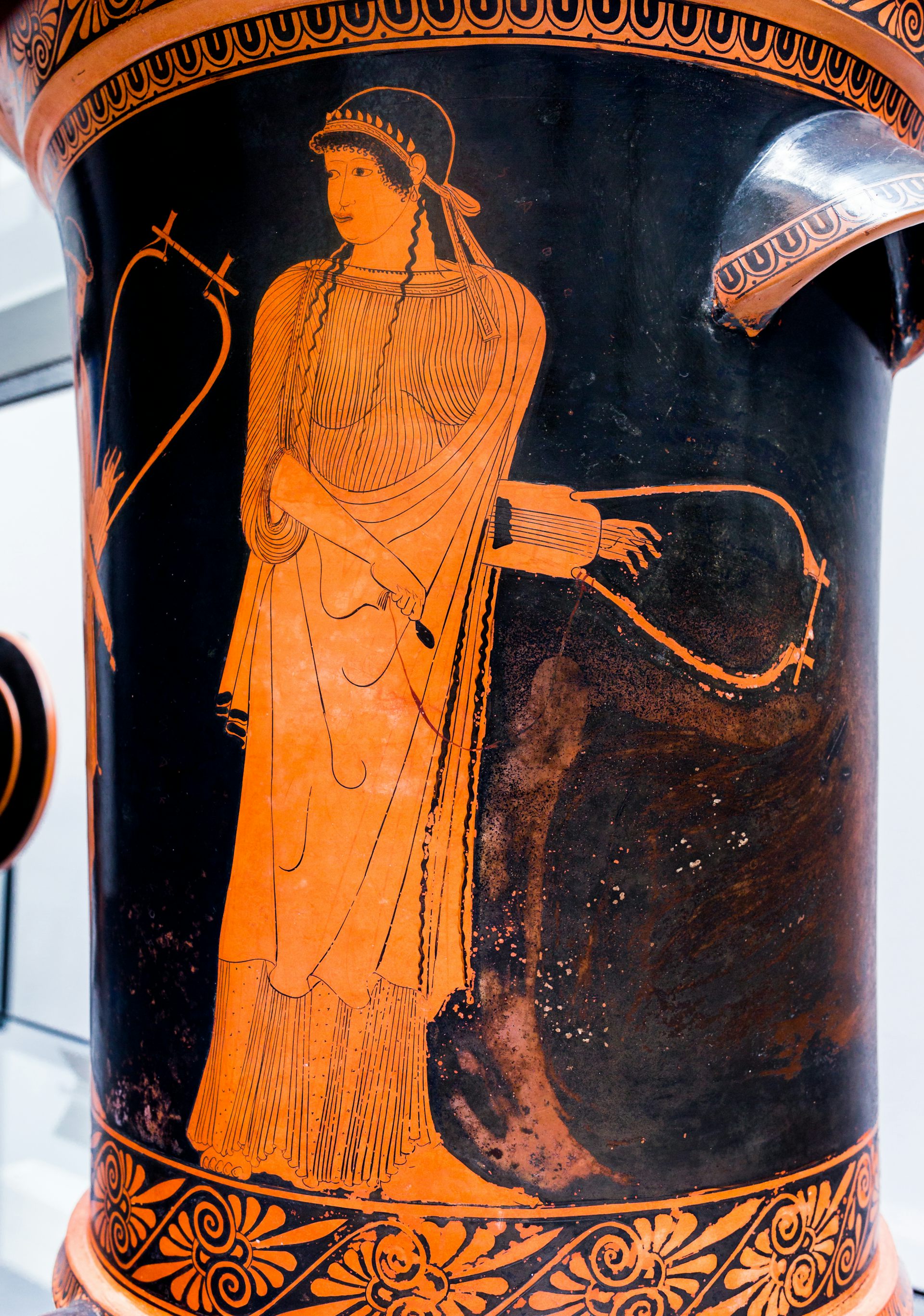 A figure holding a musical instrument gazing to the side.