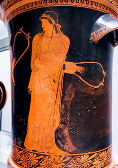 A figure holding a musical instrument gazing to the side.