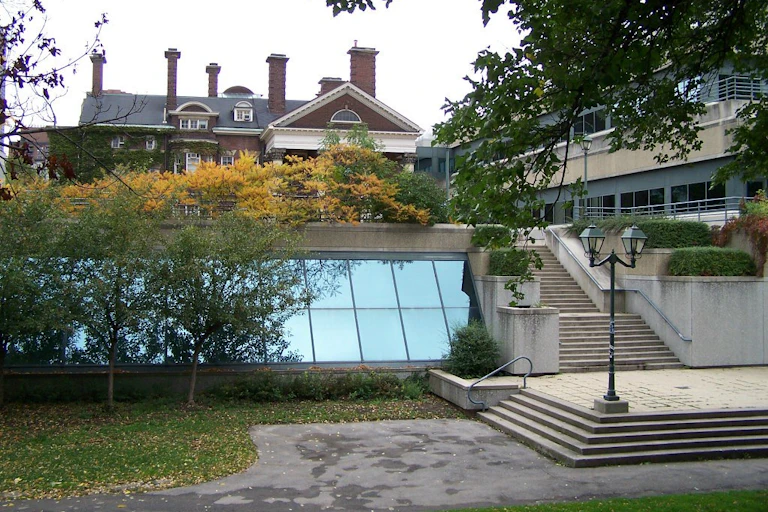 A walkway with lamppost and a stairway in front of a large house/