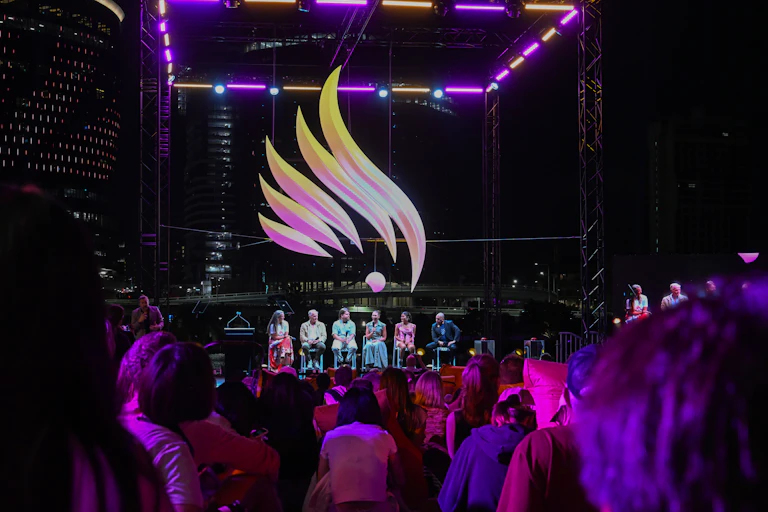 Crowds of people attend an emblem reveal event at night.