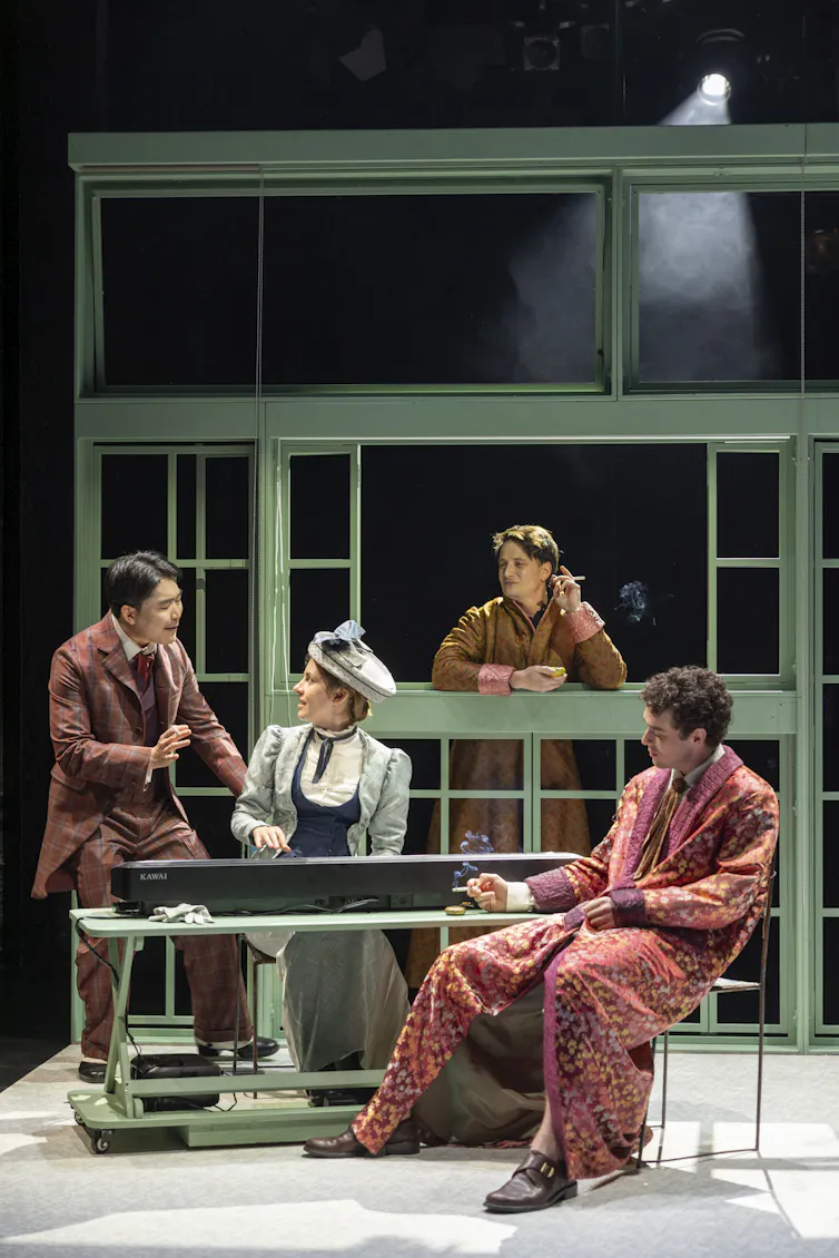 Production image: three men and a woman smoke and talk.