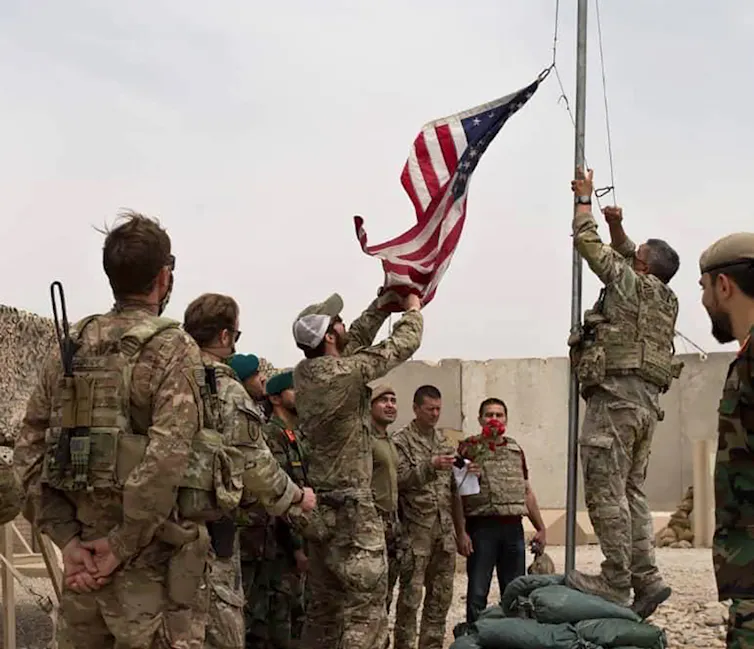 US troops lower a US flag at a military base in Afghanistan.