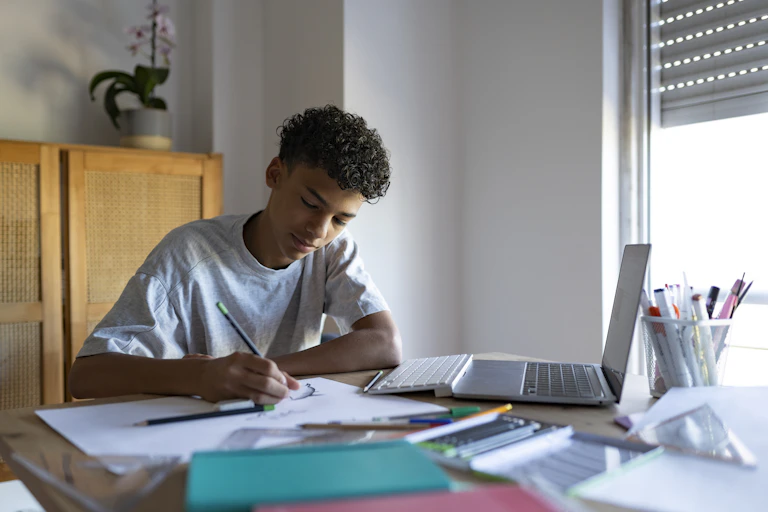 Teen boy studying on kitchen table.