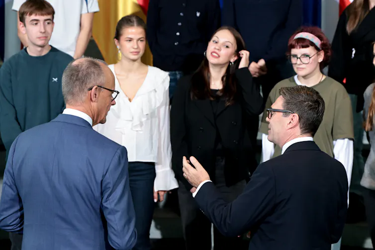 Friedrich Merz and Andy Burnham talk to students at the chancellery in Berlin.
