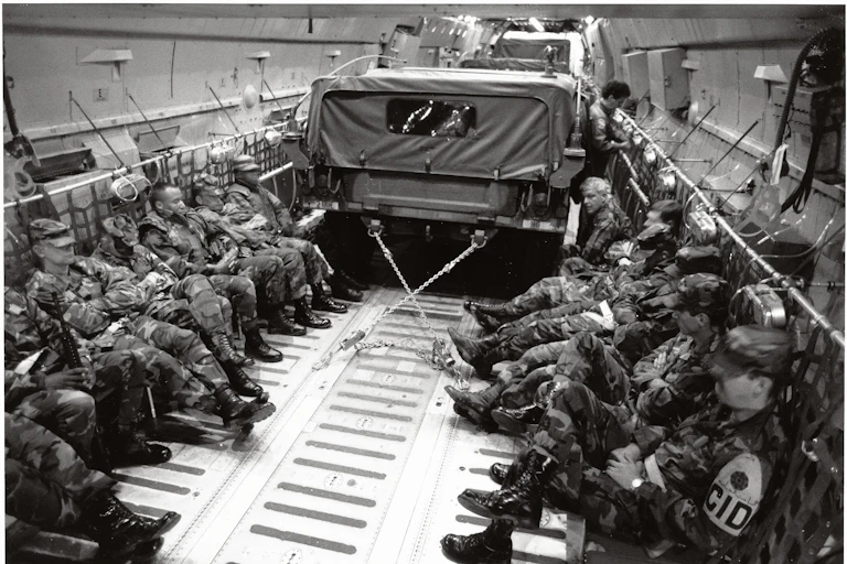 Imagen de un transporte lleno de soldados y con un camión.