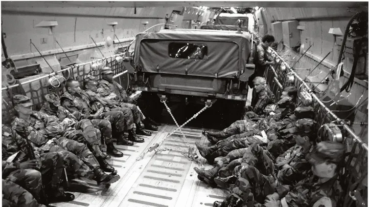 Imagen de un transporte lleno de soldados y con un camión.