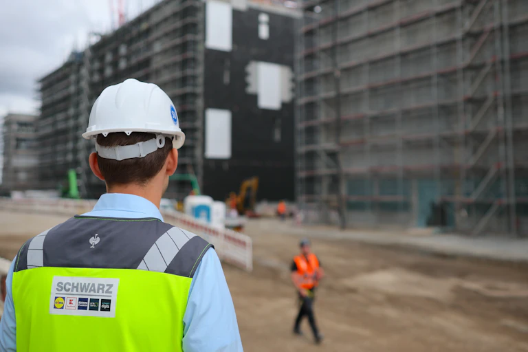 A new data centre opening in Germany, in foreground man in hard hat, building in background.