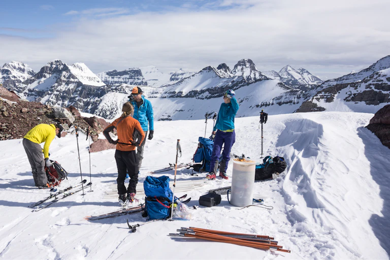 Scientists on skis stand on a glacier with mountains in the background.