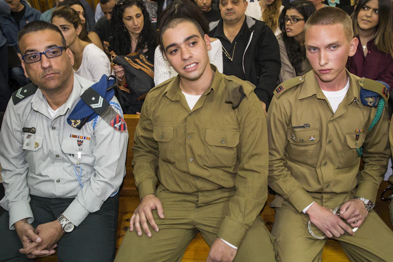 three men in uniform sit in a row.