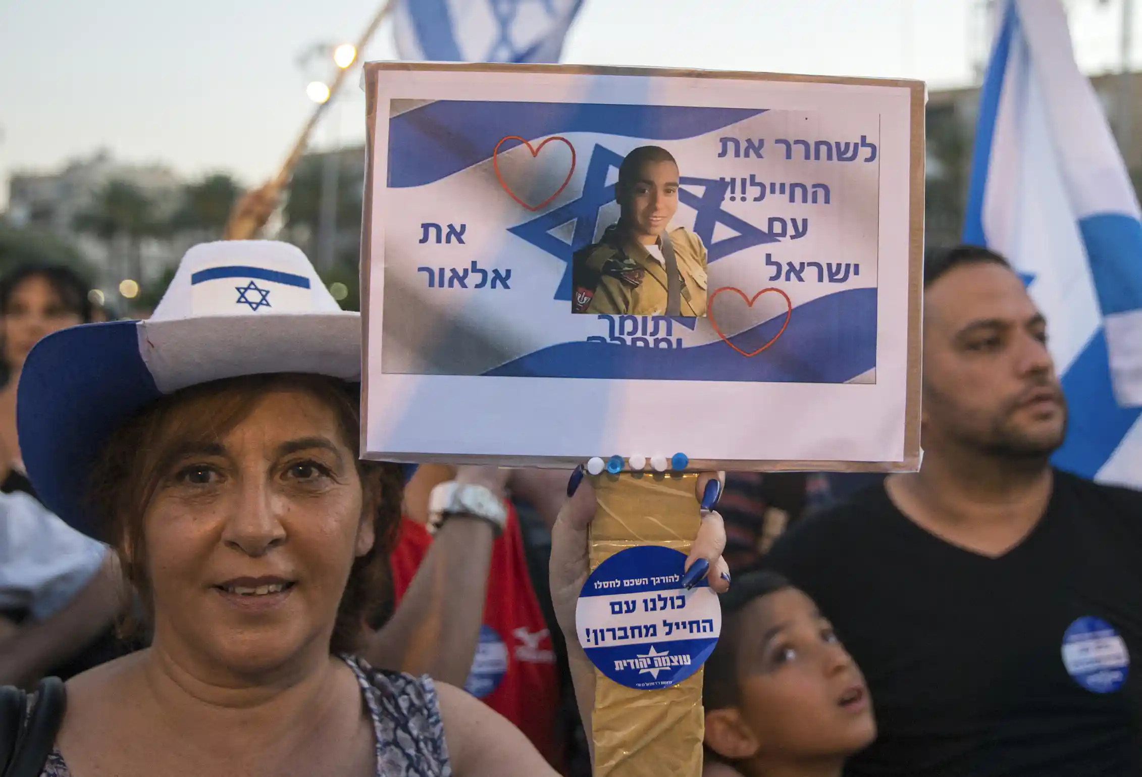 A woman holds a banner showing a man's face.