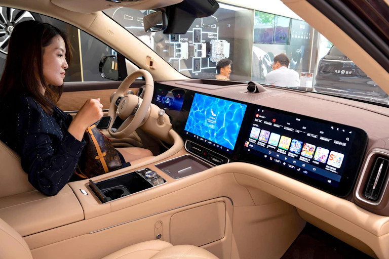 A young woman inspects the digital display inside a Huawei car in Shanghai.