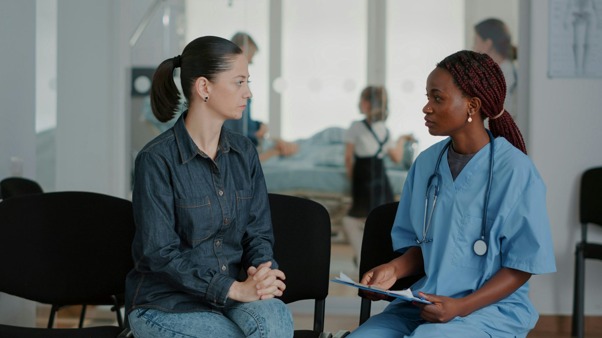A woman and a health-care provider are seated facing each other, in conversation.