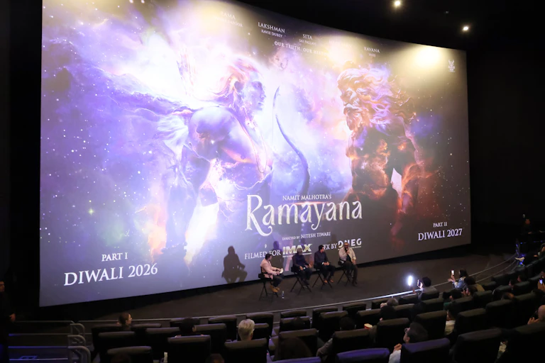 ‘Ramayana’ appears on a giant cinema screen, with two characters facing each other amid a backdrop of swirling purple and golden clouds.